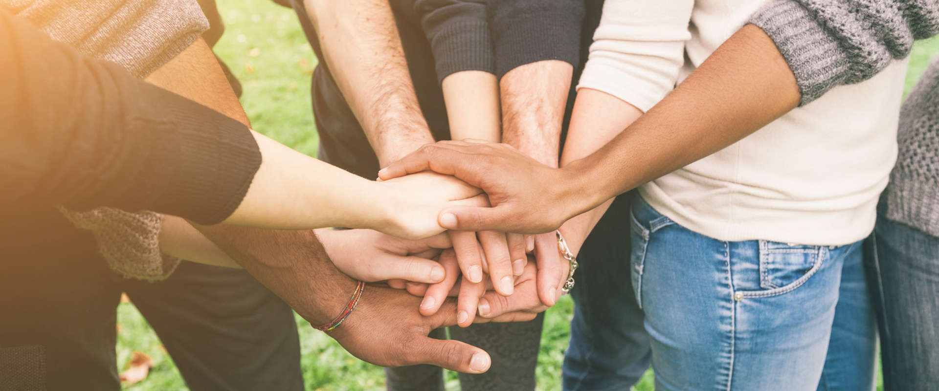 Gruppe von Menschen, die in der Mitte die Hände zusammenlegen